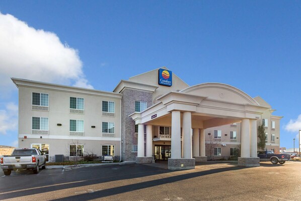 A Comfort Inn & Suites hotel with a two-story structure, a covered entrance, and a parking lot with a pickup truck.