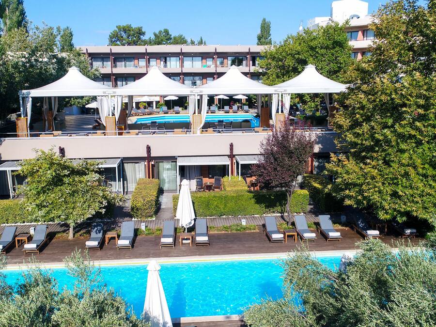 A hotel with a pool, multiple levels, outdoor seating, and a garden area.