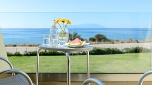 Een tafel met een bord watermeloen en waterflessen, een vaas met gele bloemen en een glas water.