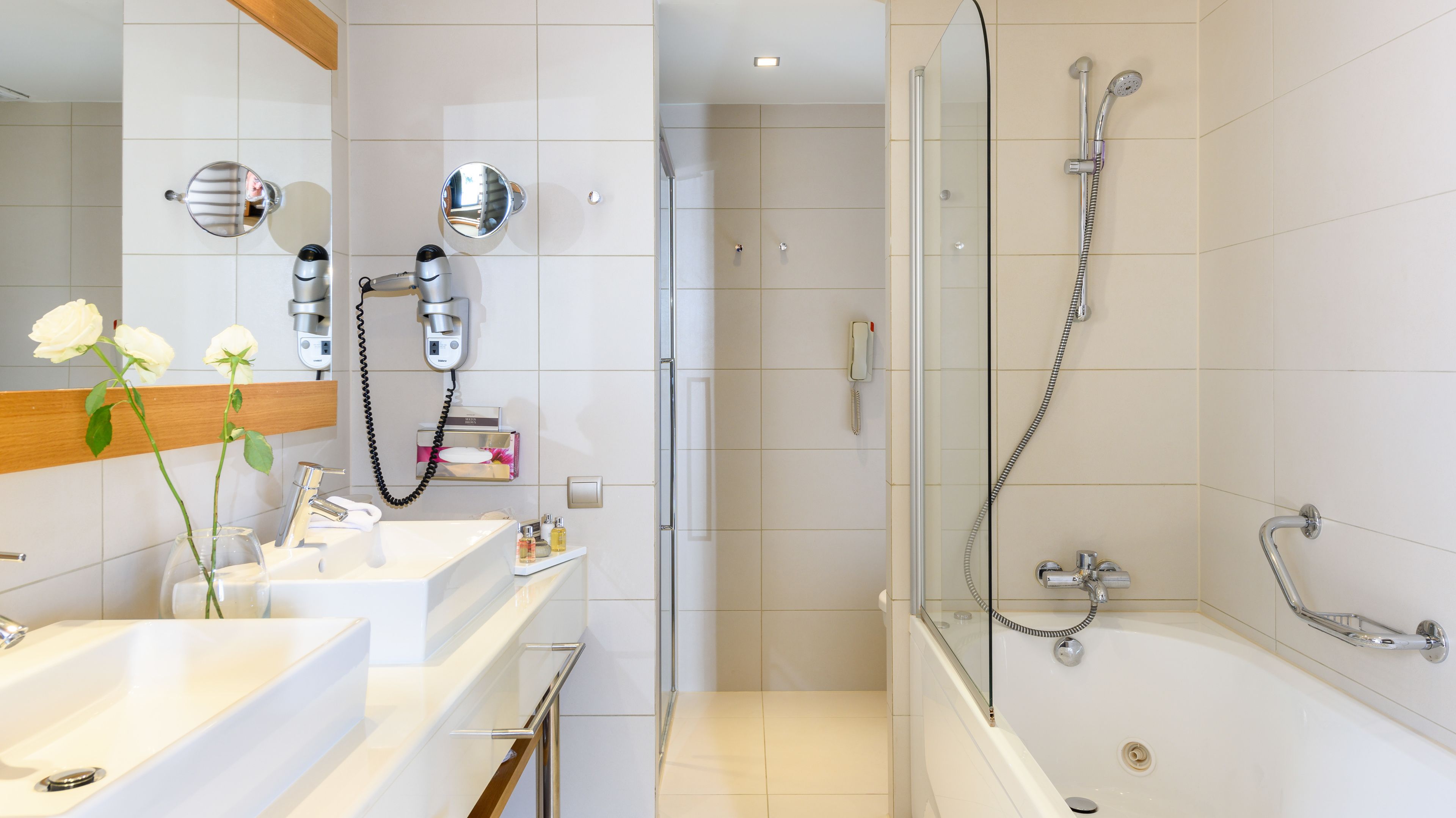 Un baño moderno con ducha envuelta en vidrio, tocador con espejo y lavamanos.