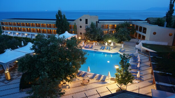 Een resort met een zwembad, ligbedden en uitzicht op zee.