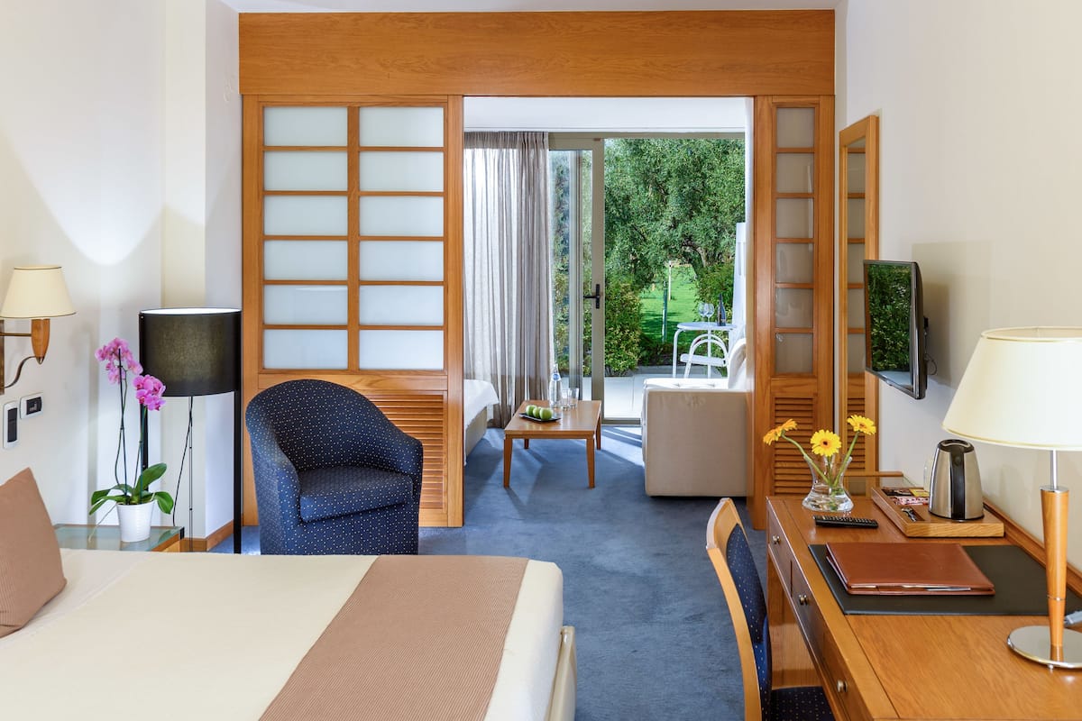 Une chambre d’hôtel équipée d’un lit, d’un bureau, d’une chaise, d’une télévision et offrant une vue sur le jardin.