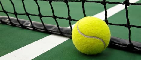 A tennis ball on a green court with white lines.