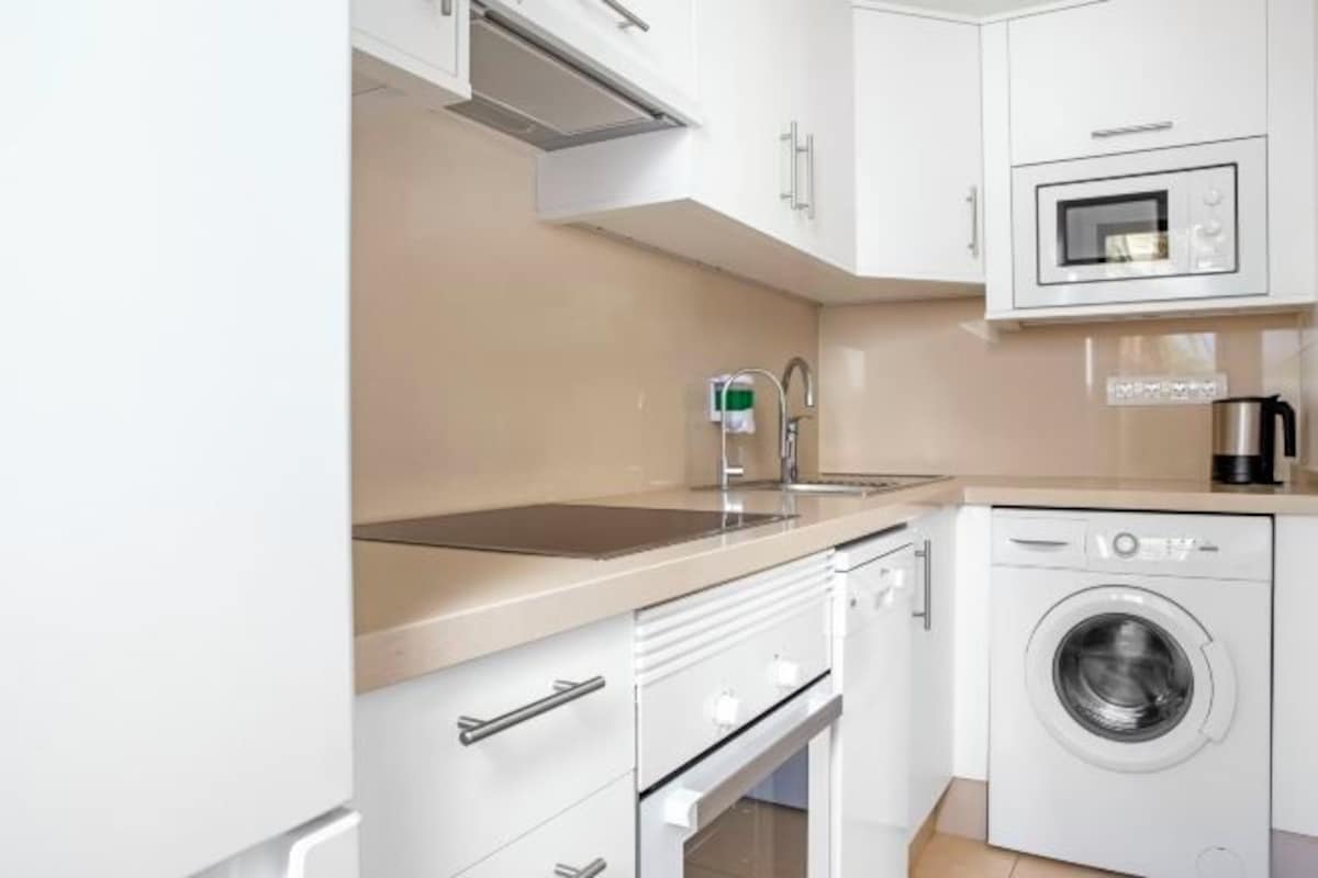 A compact kitchen with a washing machine, a microwave, and a sink.