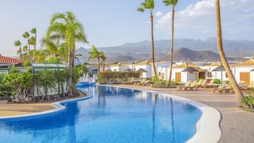 Una piscina al aire libre, sombrillas, sillones reclinables de piscina