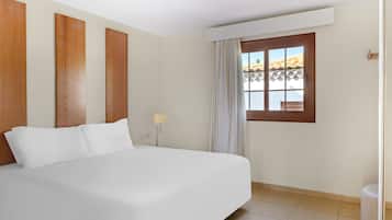 A hotel room with a large bed, a window with curtains, and a view of the outdoors.