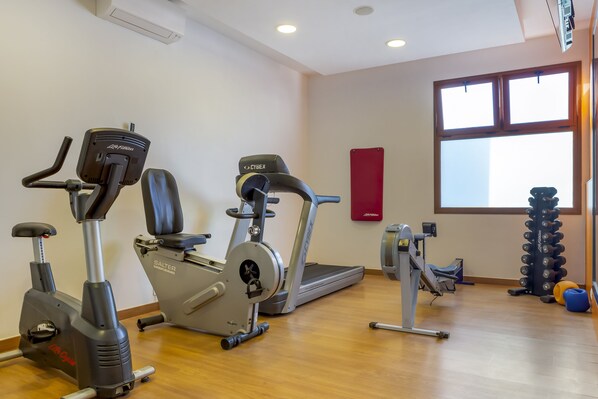 A gym with cardio machines, a treadmill, and weightlifting equipment.