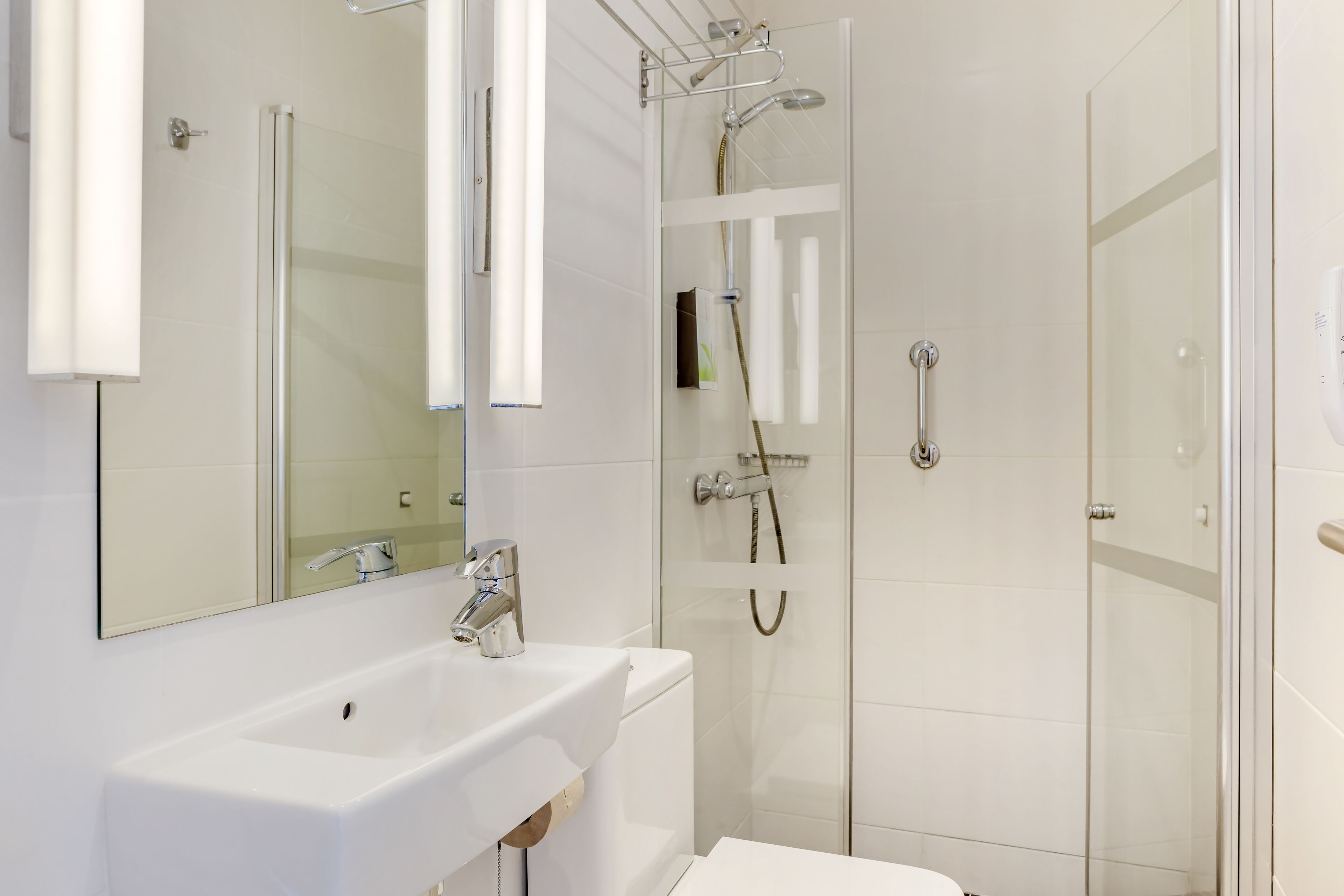 A modern bathroom with a white sink, a mirror, and a glass-enclosed shower area.