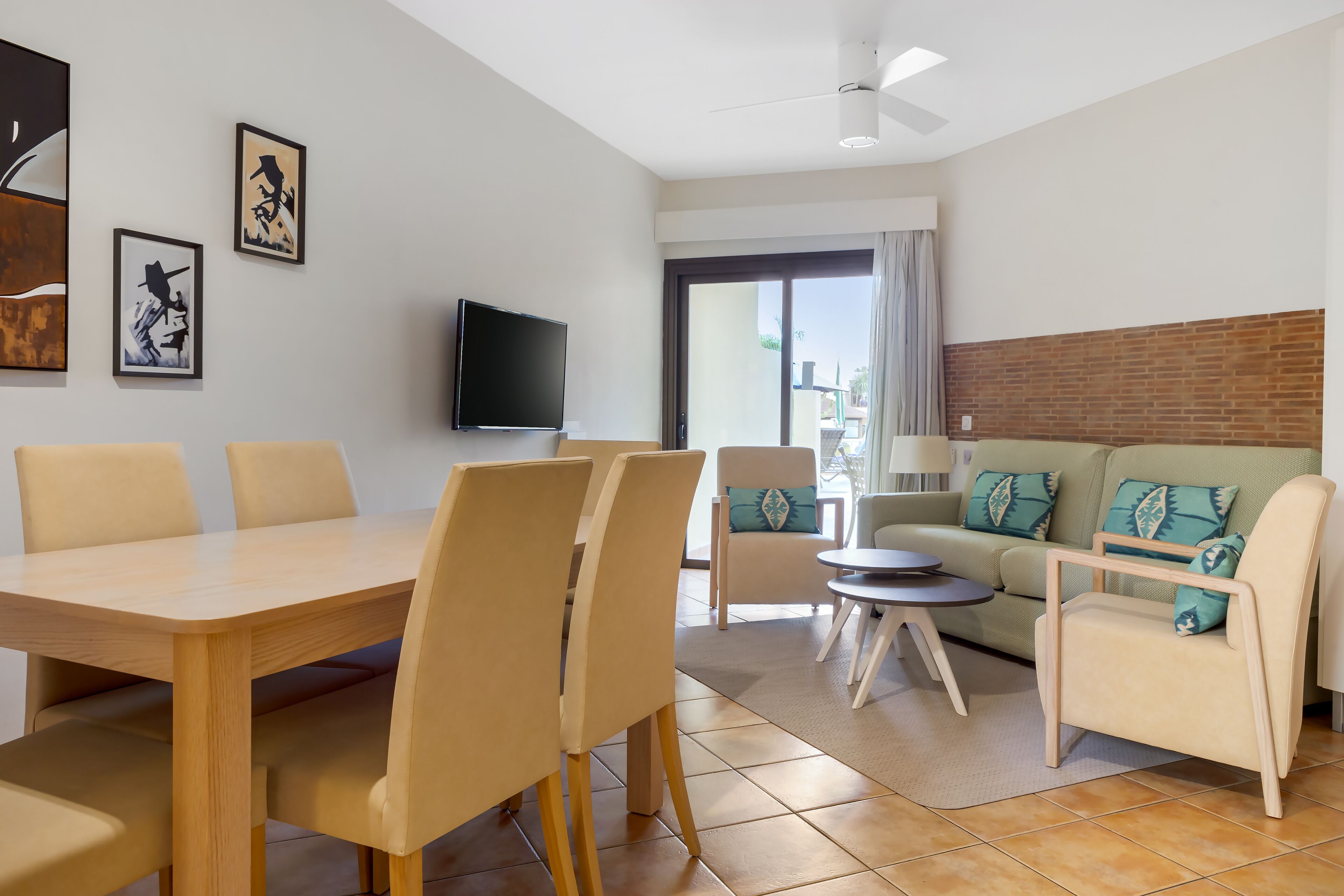 A modern living room with a dining area, a flat-screen TV, and a sofa with patterned cushions.