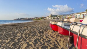 Une plage avec des chaises de sauveteur rouges et blanches, un ciel dégagé et des bâtiments en arrière-plan.