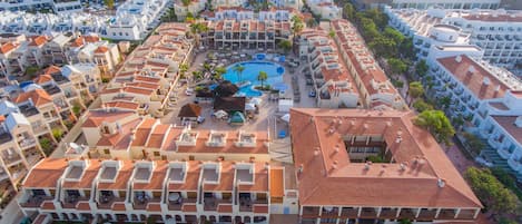 A resort with multiple buildings, a central pool area, and outdoor seating.