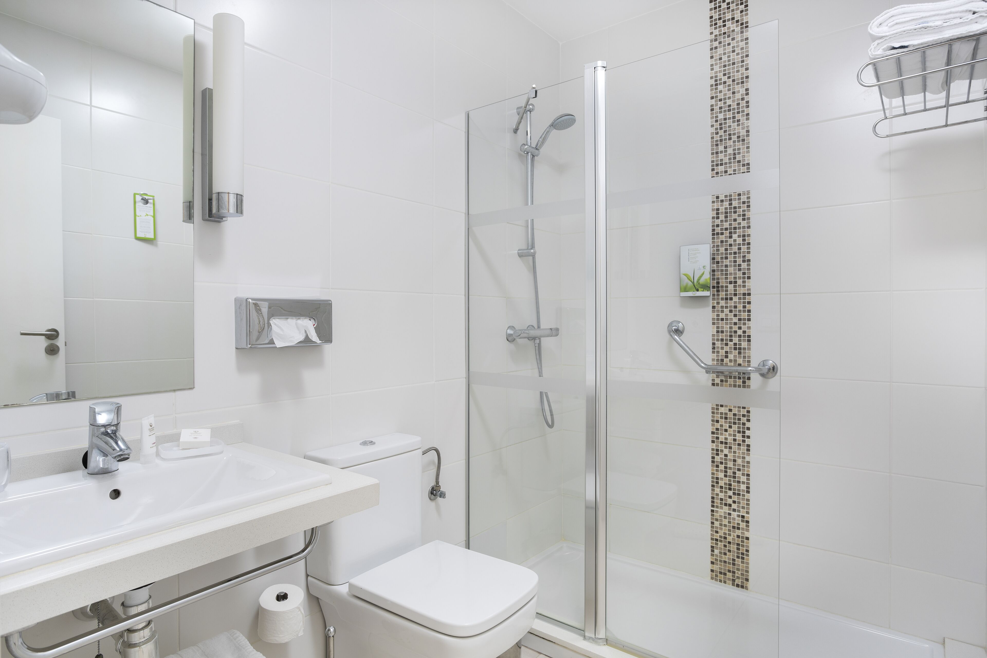 Un baño moderno con ducha acristalada, lavamanos blanco y retrete.