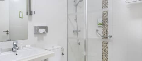 Et moderne badeværelse med en glasafskærmet brusebad, en hvid vask og et toilet.