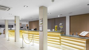 Un espace d’accueil moderne avec un comptoir en verre, un lambris en bois et une pancarte indiquant « Bienvenue chez vous ».