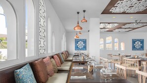 A restaurant with long communal tables, cushioned seating, pendant lighting, and decorative ceiling panels. - Sahara Sunset (Benalmádena)