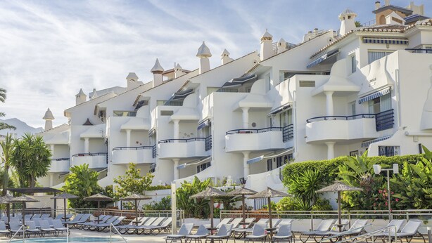 A hotel with multiple balconies, a swimming pool, and sun loungers. - Sahara Sunset (Benalmádena)