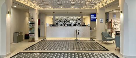 A modern reception area with a patterned floor, a reception desk, and a seating area with chairs.