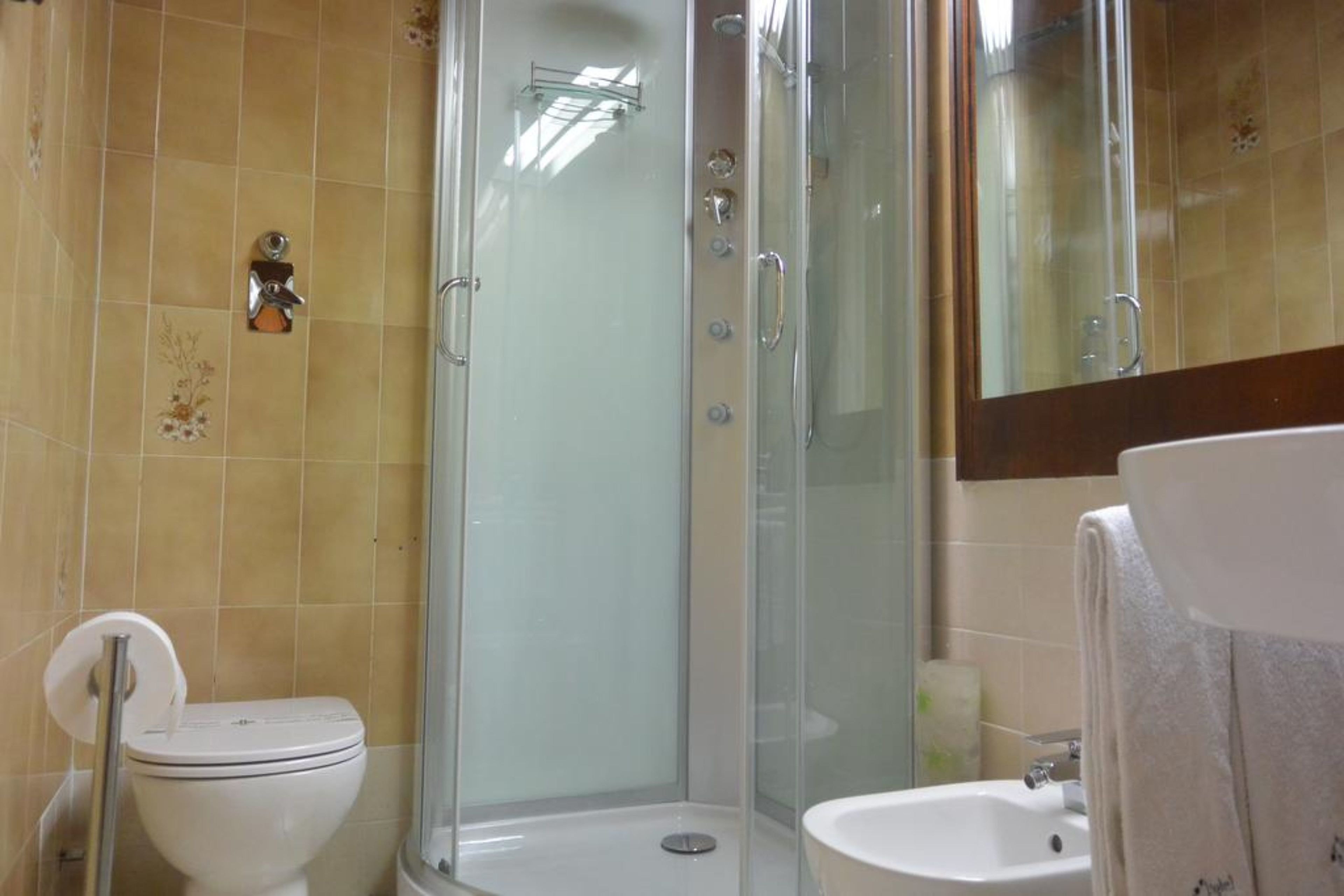 A bathroom with a glass-enclosed shower, a toilet, and a sink.