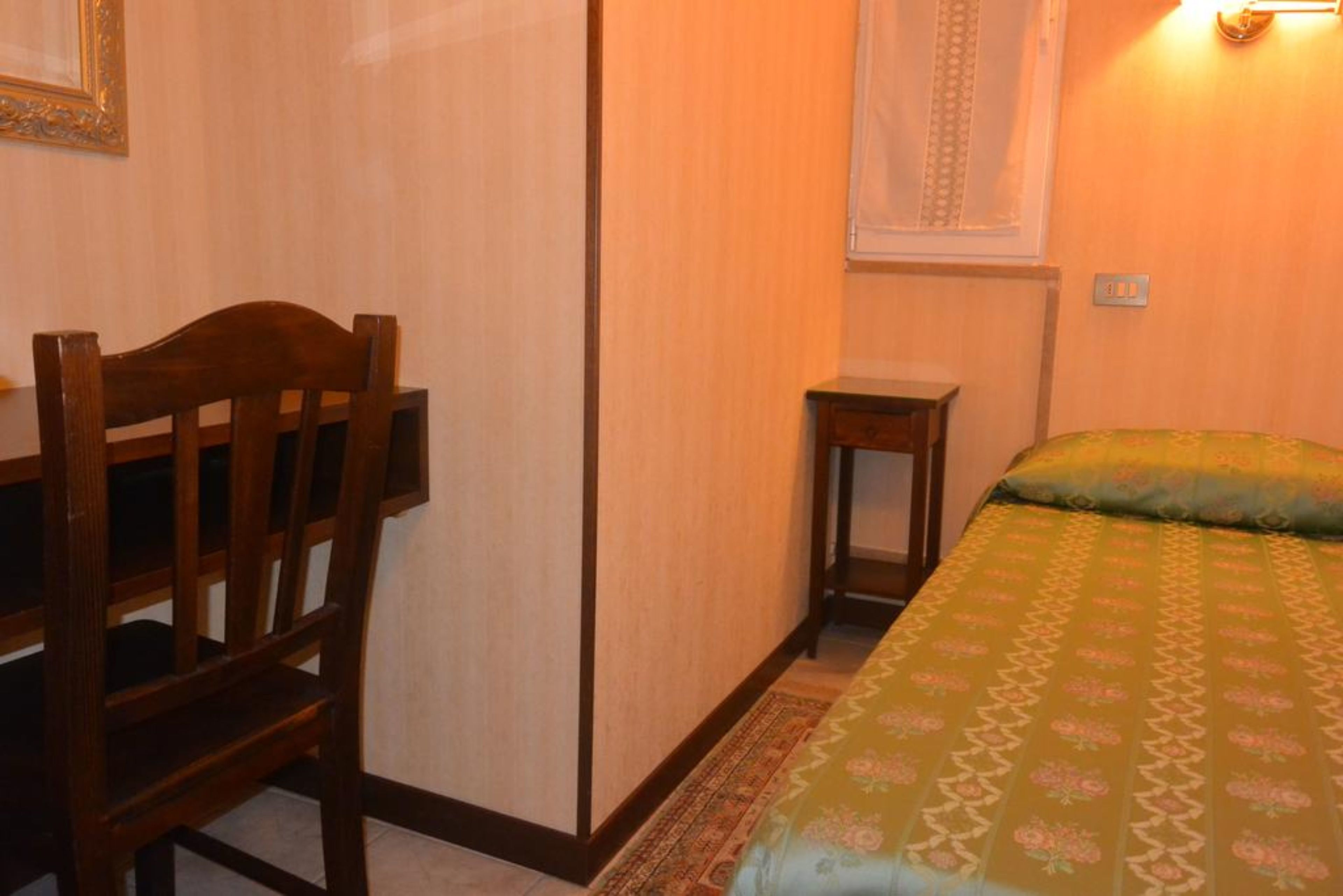 Ein Schlafzimmer mit einem Holzbett, einem kleinen Nachttisch und einem Bett mit einem gemusterten Überwurf.