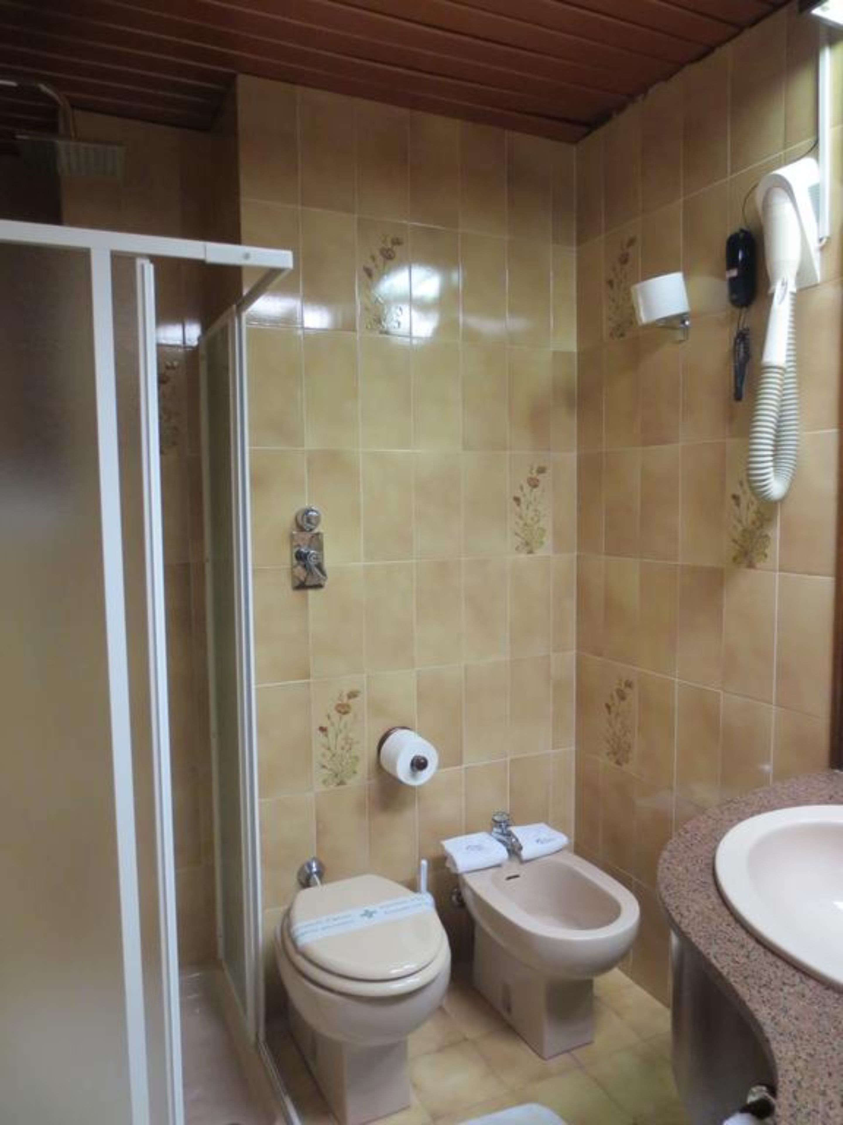 Un baño con ducha, inodoro, bidé y lavamanos.