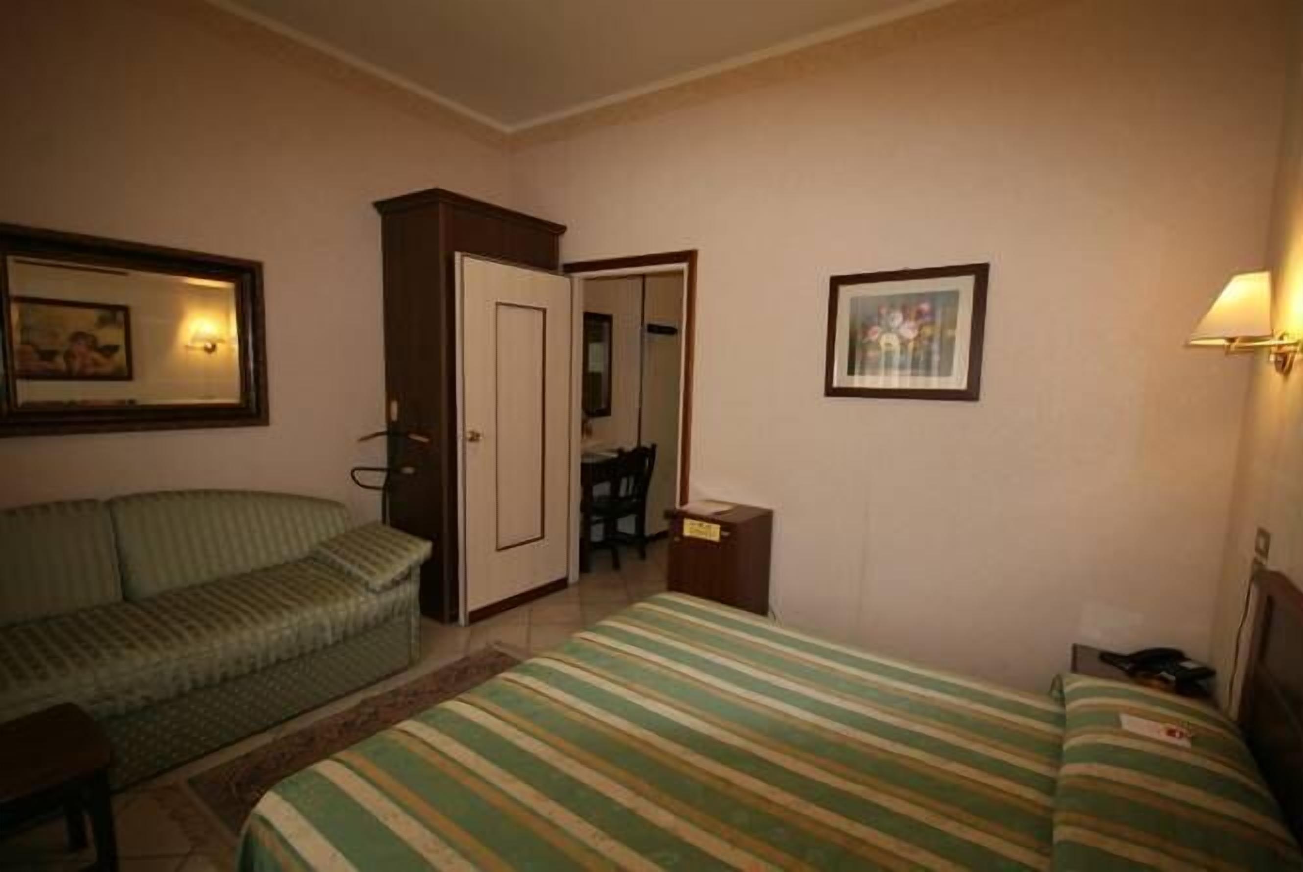 Une chambre d’hôtel avec un lit, un canapé, un bureau et une chaise.