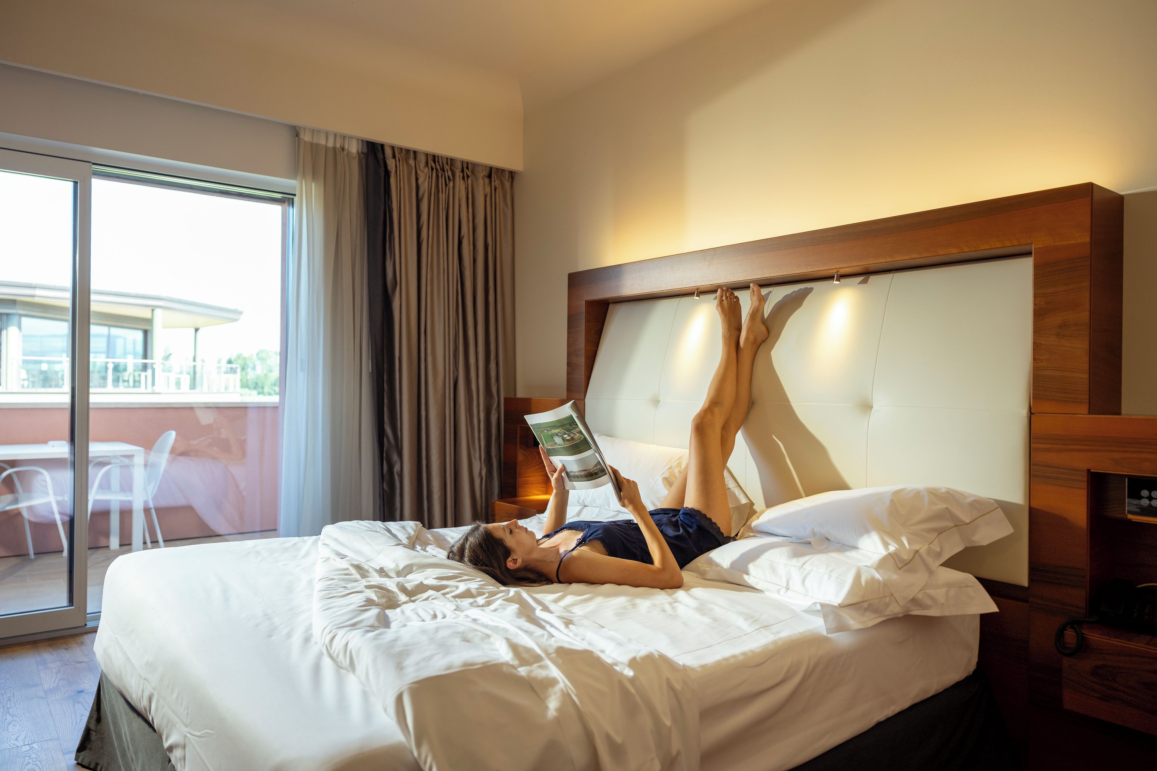 Habitación de hotel con cama, mesita de noche con teléfono y vistas al exterior.