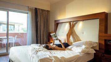 Habitación de hotel con cama, mesita de noche con teléfono y vistas al exterior.
