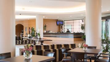En modern hotellobby med en receptionsdisk, en sittgrupp och en tv-skärm.