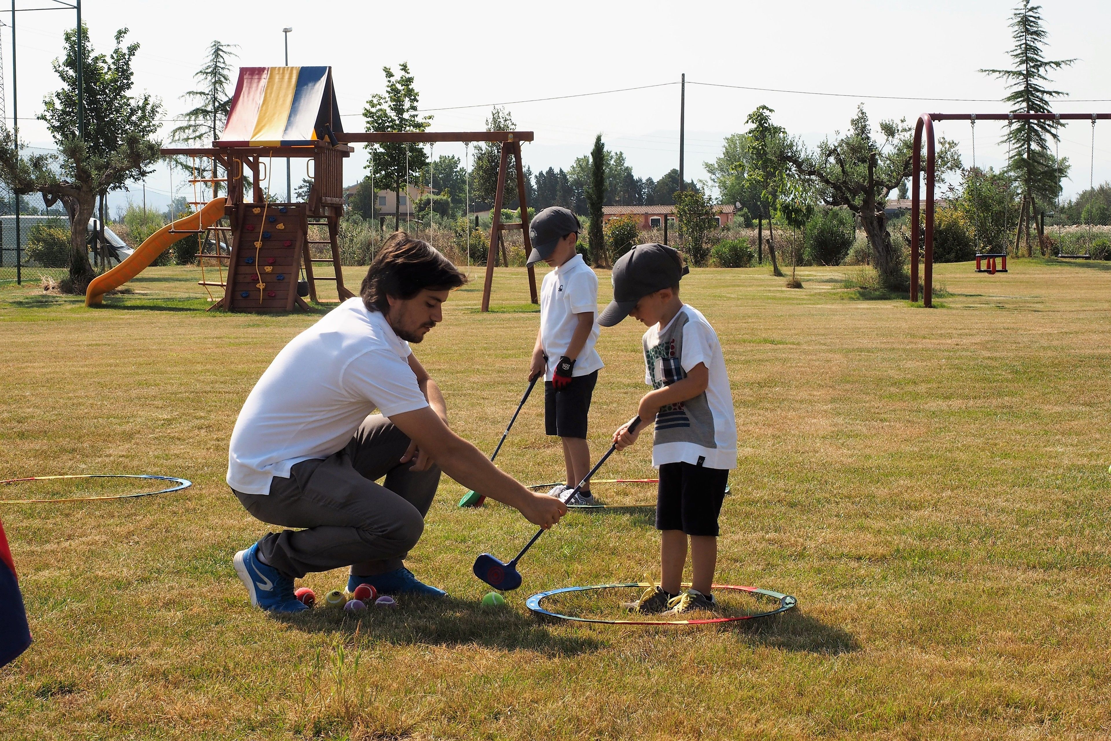 A grassy outdoor area with a playground structure, including a slide and swings.