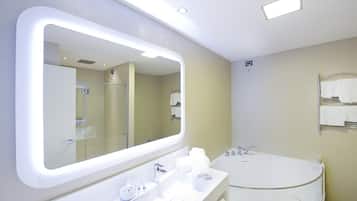 Un baño moderno con un espejo grande, una bañera redonda y un tocador con artículos de aseo.