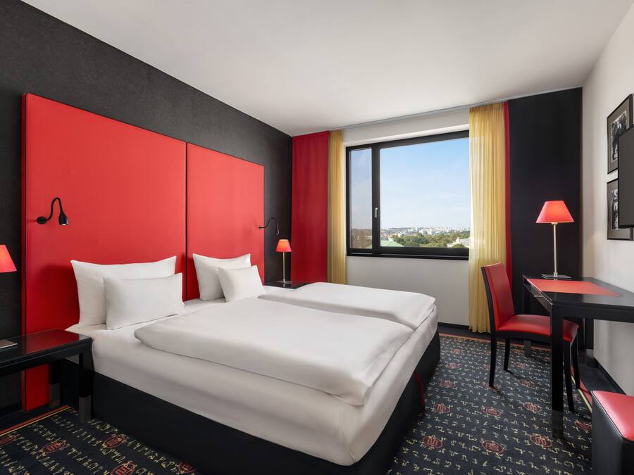 A hotel room with a large bed, two bedside tables, a desk, and a chair.
