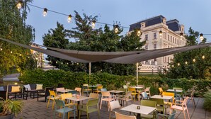Un patio al aire libre con mesas, sillas, un toldo y luces colgantes.
