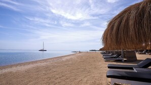 A beach with sun loungers and a thatched umbrella. - Ali Pasha Hotel El Gouna (El Gouna)