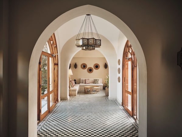 A hallway with checkered flooring, an arched ceiling, and a central seating area with a table and chairs.