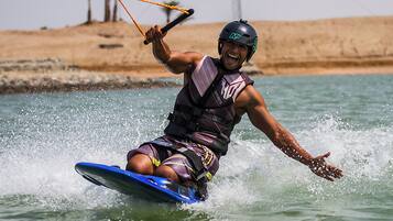 A person water skiing on a blue board, wearing a life vest and helmet.