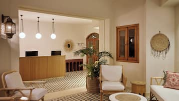 Um hall de entrada com balcão de recepção, área de check-in, espaço de estar e piso xadrez.