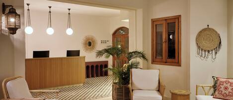 A lobby with a reception desk, check-in counter, seating area, and a checkered floor.