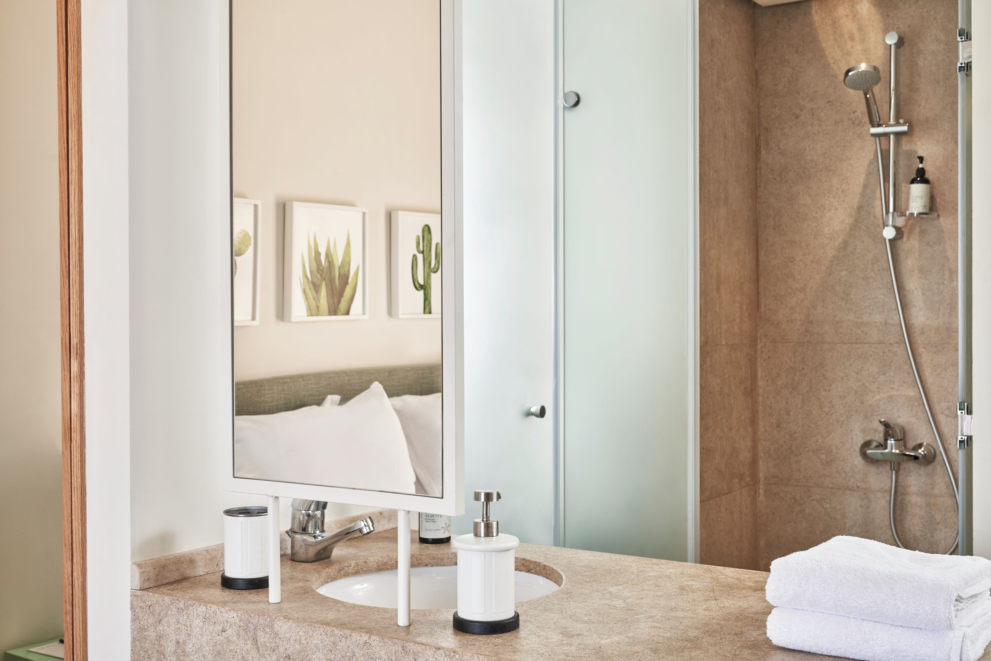 A bathroom with a sink, mirror, and shower.