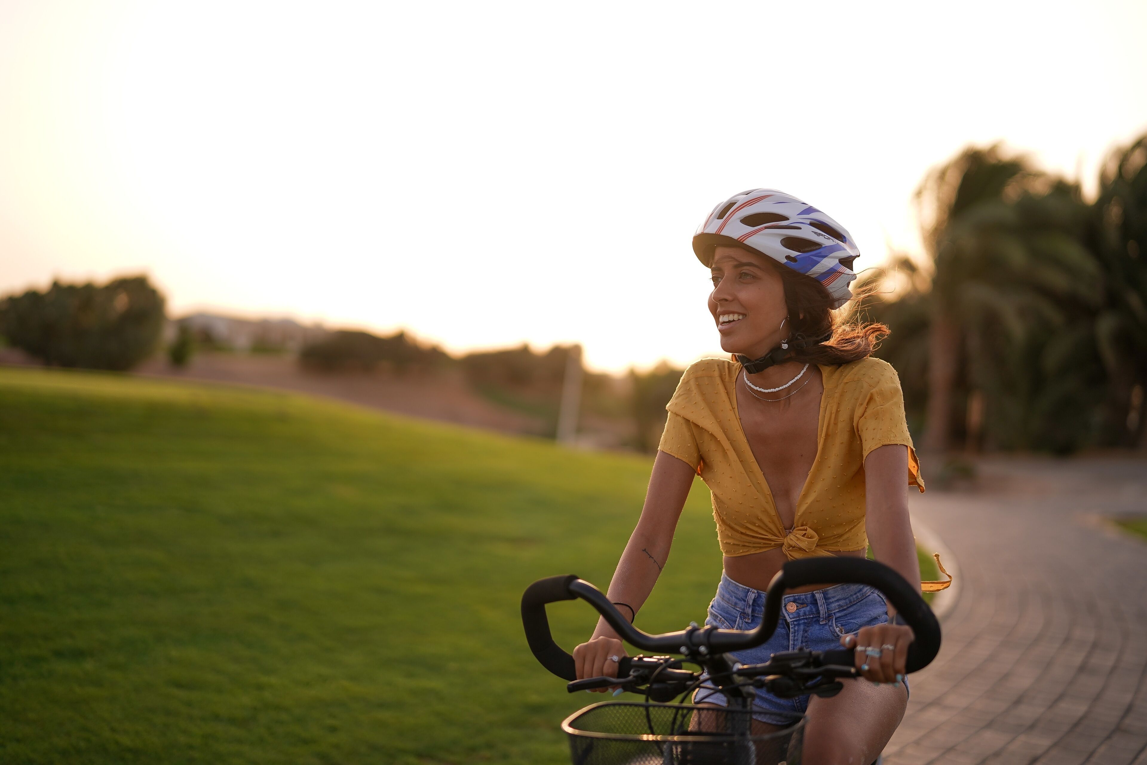 Eine Person fährt auf einem Radweg, der von Grasflächen gesäumt wird.