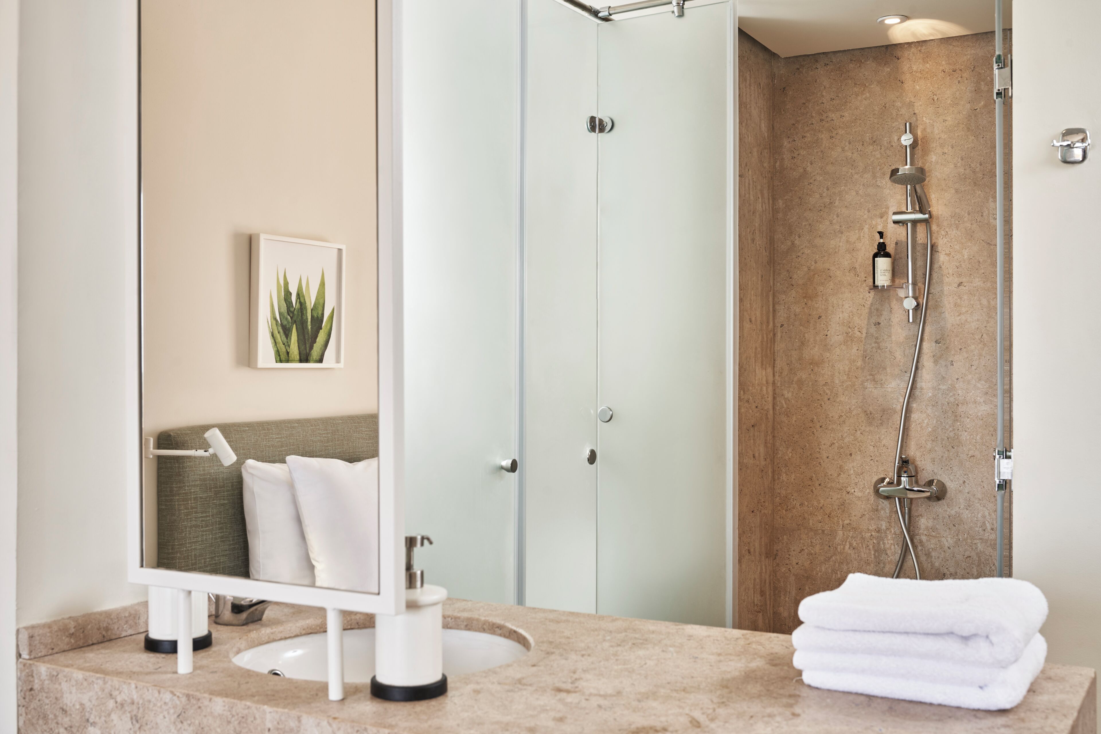 A modern bathroom with a sink, mirror, and a shower with a handheld showerhead.
