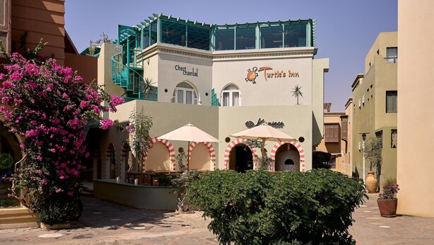 Ein Gebäude mit der Aufschrift "Chez Chantal" und "Turtle's Inn", mit Außenplätzen und Sonnenschirmen.