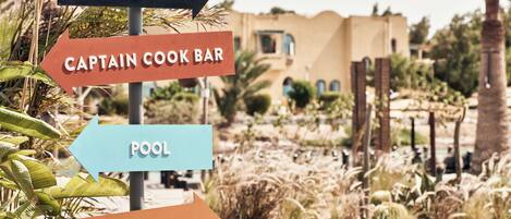 Directional signs for Cantina, Captain Cook Bar, Pool, and Beach.
