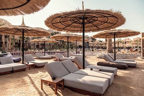 Een privéstrand, ligstoelen aan het strand, parasols, strandlakens