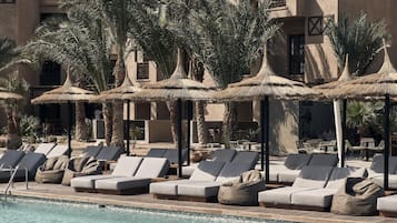 Relax by the pool with a lounger and umbrella, surrounded by a tranquil resort setting.