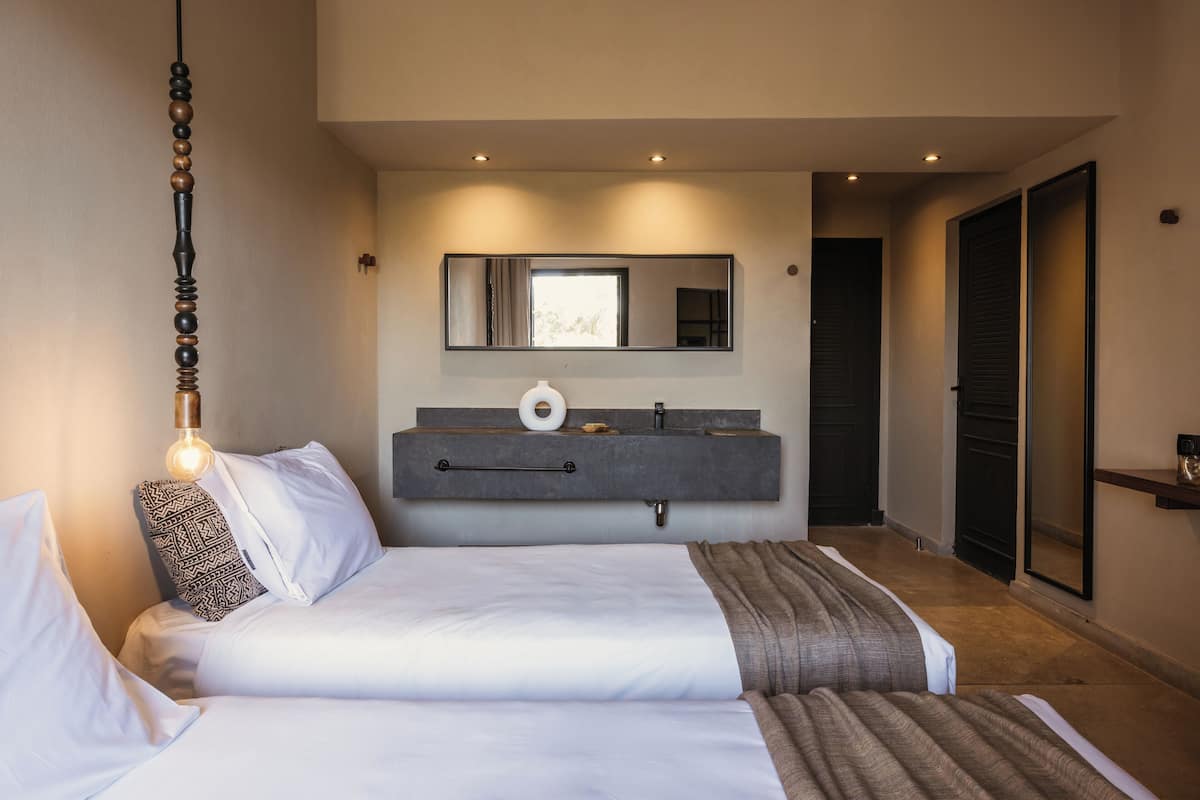 Une chambre à coucher comprenant un lit, une table de chevet, un miroir et une coiffeuse intégrée avec un lavabo.