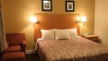 Habitación de hotel con una cama, dos lámparas fijadas a la pared, una silla y una mesita de noche con un teléfono.