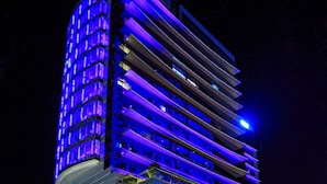 Een modern hotel met een golvende gevel, meerdere verdiepingen en verlichte balkons.