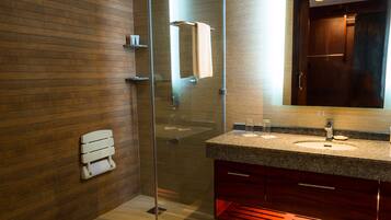 Un baño moderno con cabina de ducha de vidrio, pared de madera, lavamanos de mármol y barra para toallas.