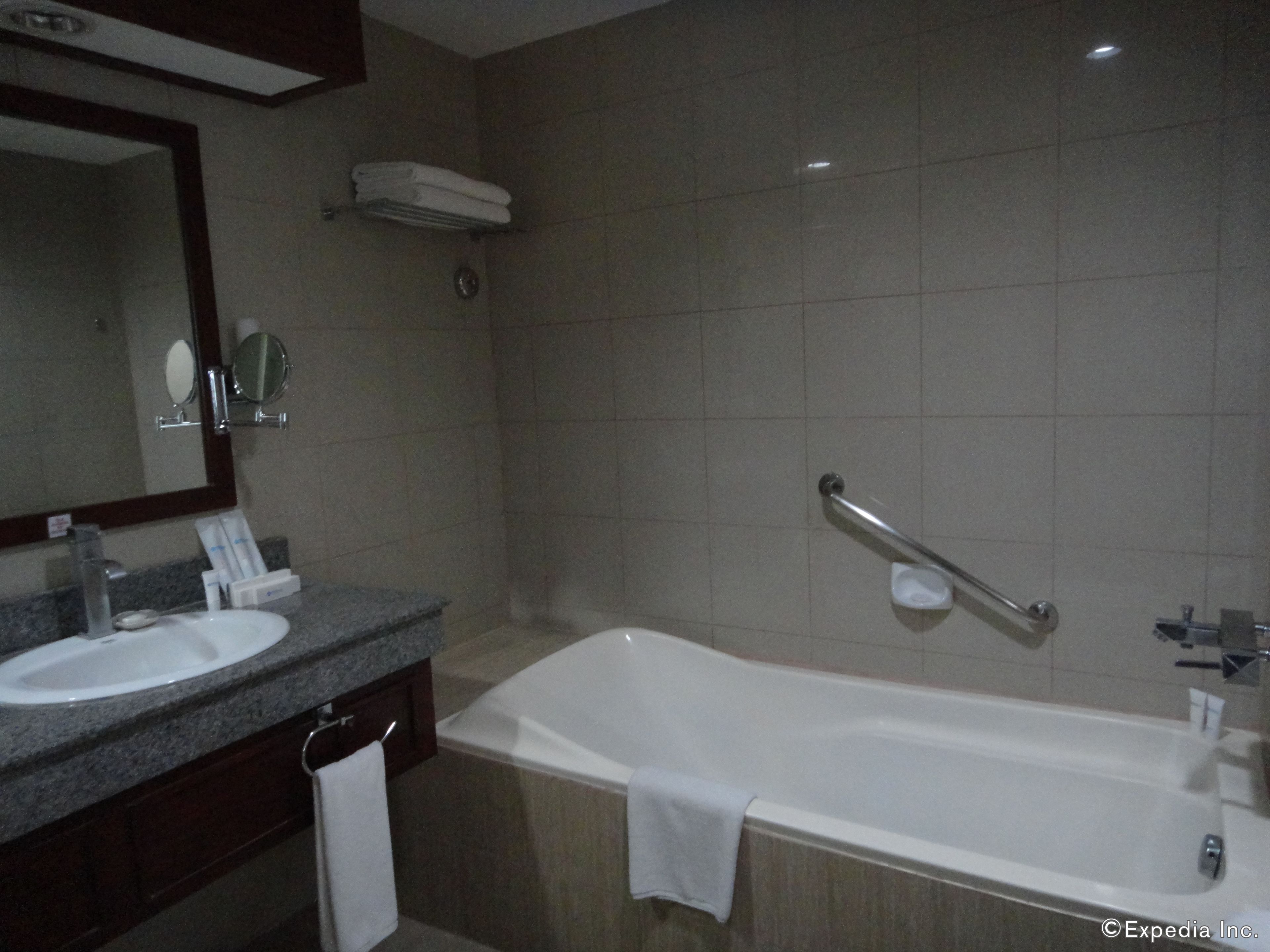 A bathroom with a sink, mirror, and bathtub.