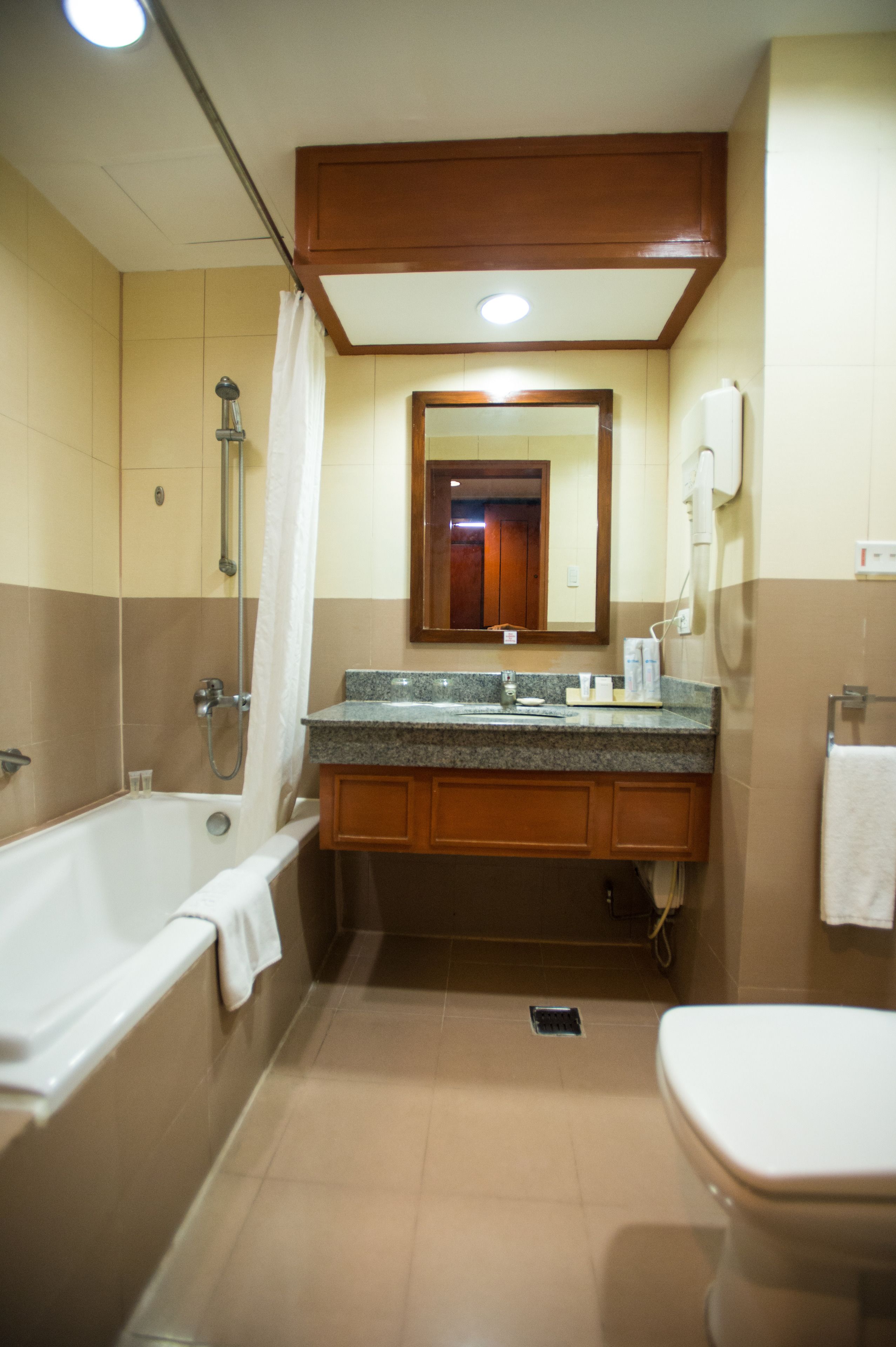 A bathroom with a bathtub, sink, mirror, and toilet.